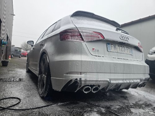 Trois-quarts arrière d'une Audi S3 blanche pendant le lavage extérieur