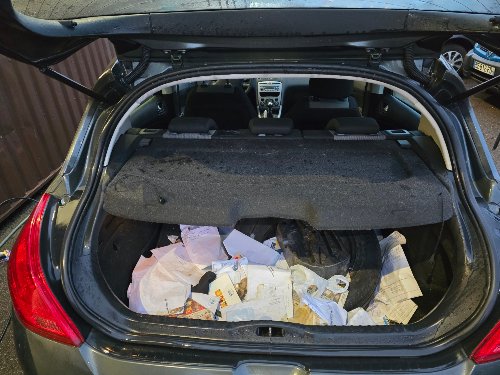 Coffre d'une Peugeot 308 rempli de papiers avant vidage et aspiration