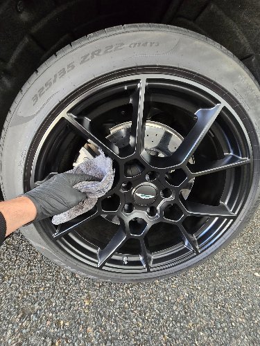 Nettoyage détaillé d'une jante d'Aston Martin, gant microfibre à la main