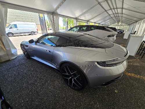 Aston Martin DB12 argentée vue de profil sous chapiteau
