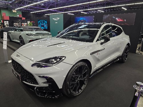 Aston Martin DBX blanche préparée, vue de trois-quarts en showroom