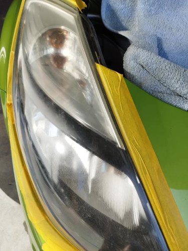 Phare d'une Citroën verte masqué à l'adhésif, opacifié et taché avant rénovation