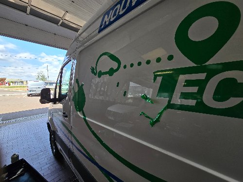 Détail du lettrage publicitaire vert sur un Mercedes Sprinter avant décollage
